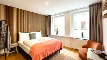 Ein modernes Schlafzimmer mit Bett, Stuhl, Schreibtisch und einem Fenster mit Vorhängen.