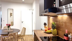A modern kitchen with a built-in microwave, a wooden countertop, and a dining area with wicker chairs and a vase of flowers.