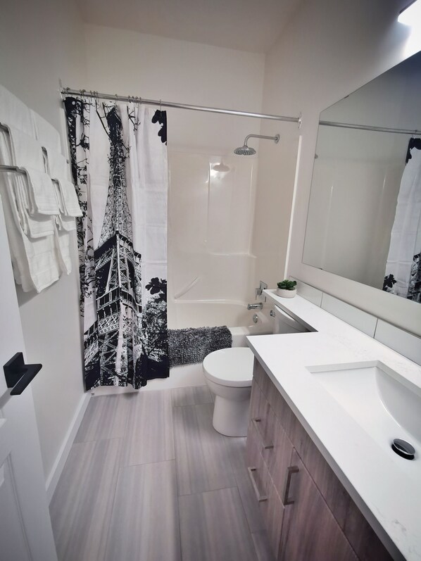 A modern bathroom with a shower, toilet, and sink.