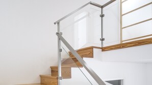 Una escalera moderna con escalones de madera y barandillas de vidrio.
