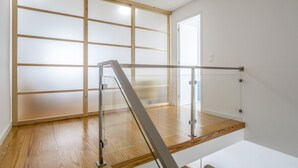 Un interior moderno con suelo de madera, barandilla de cristal y puerta corredera.