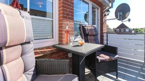 Une terrasse avec une table et des chaises en osier, un mur en briques et une antenne parabolique.