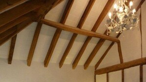 Un dormitorio con techo de madera, una cama con ropa de cama blanca, dos lámparas de noche y un candelabro.