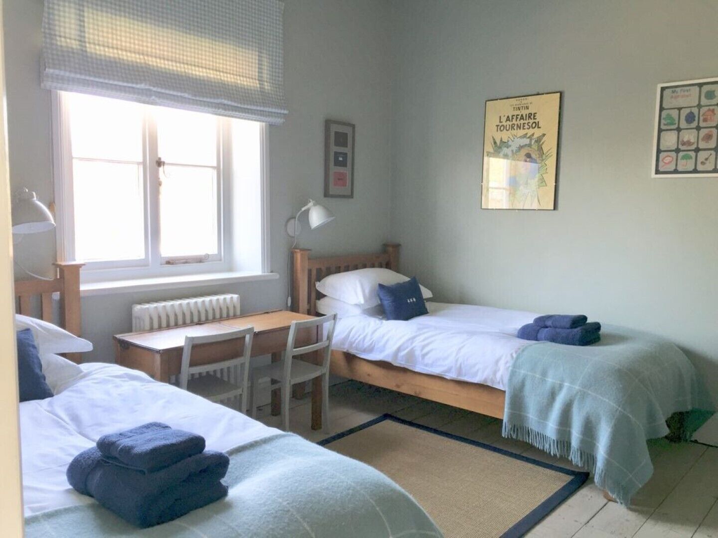 A room with two beds, a desk, and a window with a view.