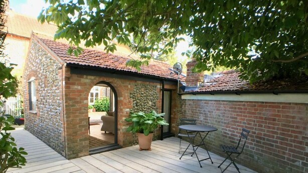 A patio area with a stone-built structure, a potted plant, and a table with chairs.