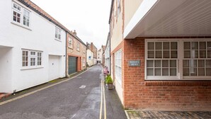 A narrow street with buildings on either side, including a sign for 'Bishop's Mews'.