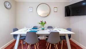 A dining room with a white table, blue chairs, and a vase with flowers.