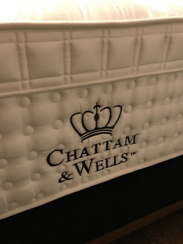 A white upholstered headboard with a quilted pattern and the logo "Chattam & Wells". - Historic day laborer's house (Geisingen)