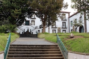 Un escalier en pierre mène à un bâtiment blanc doté de nombreuses fenêtres et d’une porte verte.