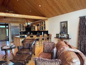 A spacious living area with a wooden ceiling, leather furniture, and a kitchen with wooden cabinets and a stainless steel refrigerator. - Elk Run Ranch…Come enjoy the breath taking views of Paradise Valley & YNP (Emigrant)