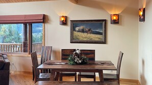 A dining area with a wooden table, chairs, and a painting on the wall. - Elk Run Ranch…Come enjoy the breath taking views of Paradise Valley & YNP (Emigrant)