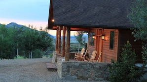 A rustic cabin with a stone foundation, wooden exterior, and a porch with two chairs. - Elk Run Ranch…Come enjoy the breath taking views of Paradise Valley & YNP (Emigrant)