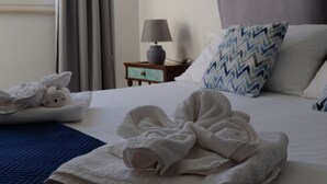 A neatly made bed with white towels, a blue patterned pillow, and a grey headboard.