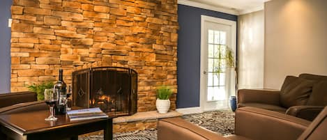 A living room with a stone fireplace, brown leather sofa, and a patterned carpet.