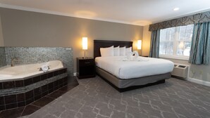 A hotel room with a large bed, a separate bathroom with a bathtub, and a window with curtains. - Golden Apple Inn (Glen)