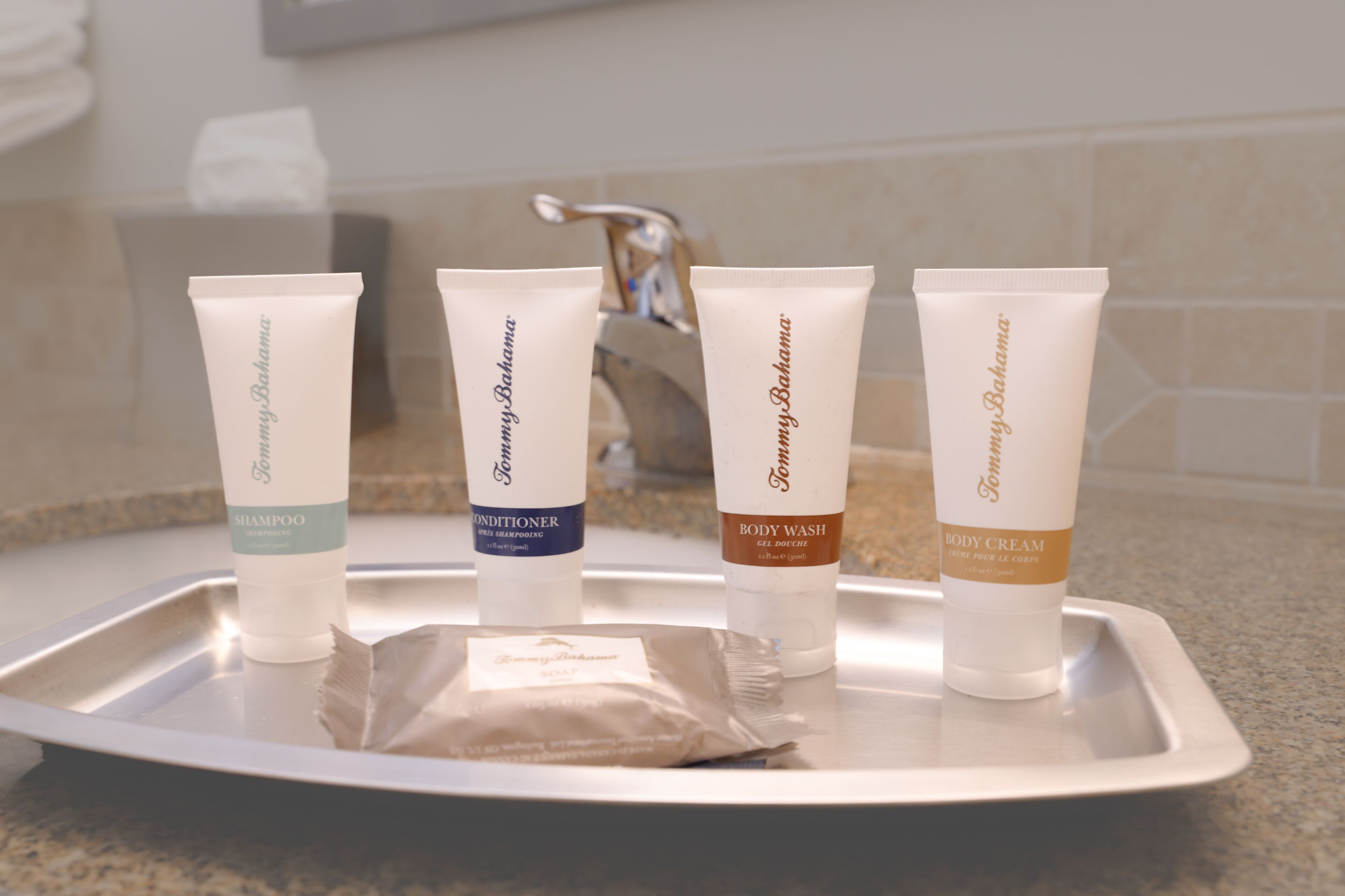 Quatre articles de toilette disposés sur un plateau dans une salle de bain.