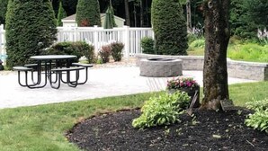 A landscaped garden with a picnic table, neatly trimmed hedges, and a stone planter. - Golden Apple Inn (Glen)
