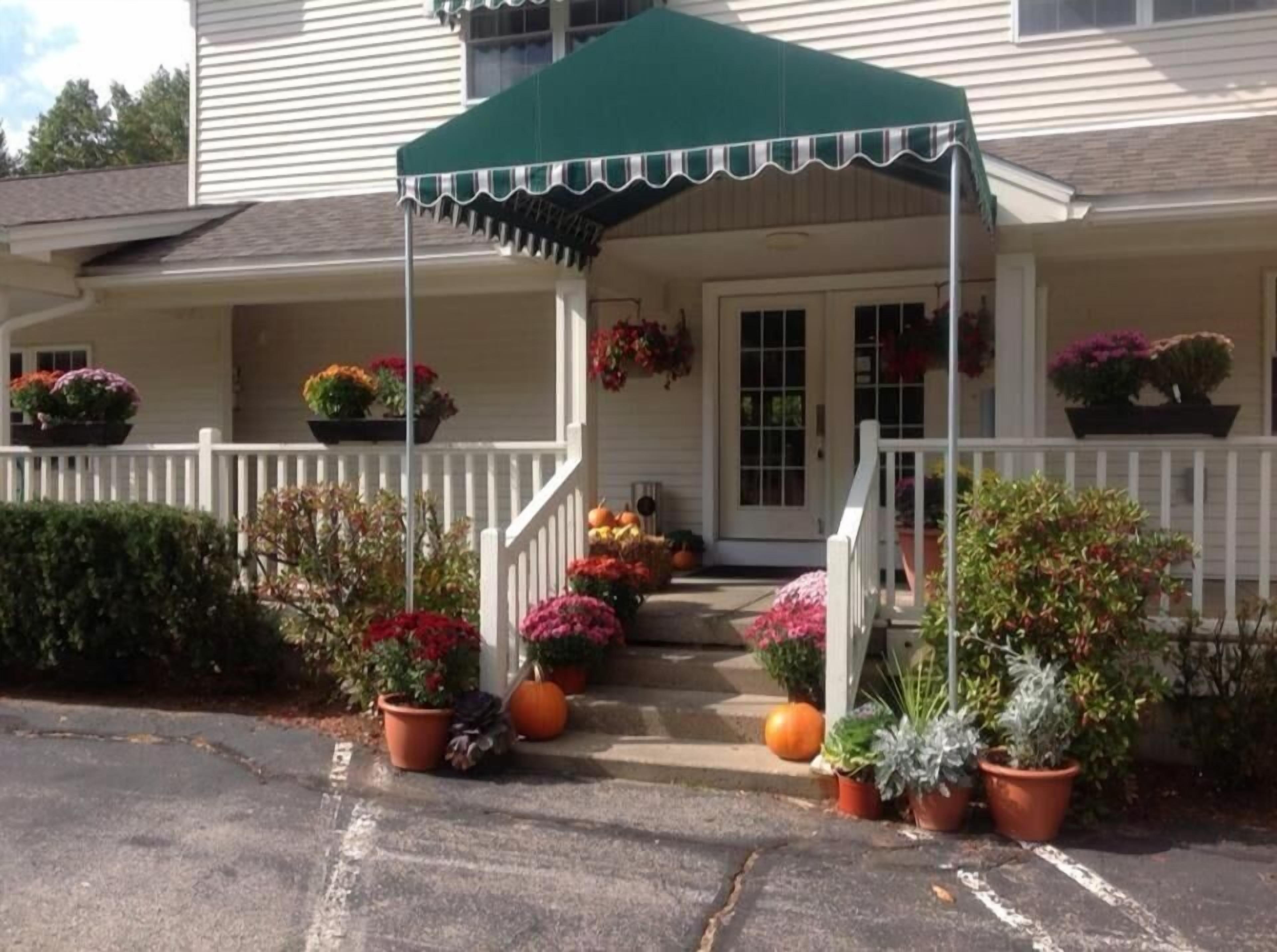 A house with a porch, white railings, and potted plants.