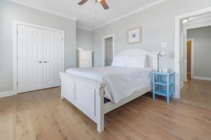 A bedroom with a white bed, a blue nightstand, and a white dresser.