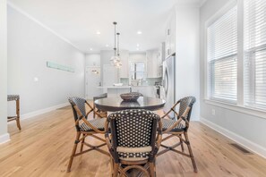 A modern kitchen with white cabinetry, a round dining table, and four wicker chairs.
