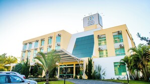 Un hotel moderno con un letrero llamativo, múltiples ventanas y un área de entrada cubierta.