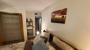 A bedroom with a bed, a nightstand, a wall-mounted lamp, a painting, and a wardrobe. - Tomar Park Apt 3 - KP101APT3 (Sioux Falls)