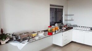 Una cuina moderna amb armaris blancs, taulell de granat i diversos electrodomèstics.