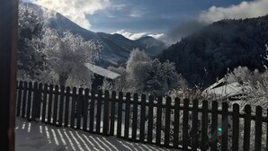 Paisaje montañoso nevado con una valla de madera en primer plano.