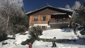 Una cabaña de madera con balcón, rodeada de nieve y árboles.