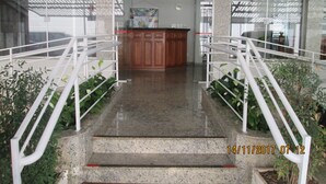 Eine Hotelhalle mit einer zentralen Rezeption, einer Treppe mit Metallgeländern und einer Glastrennwand.