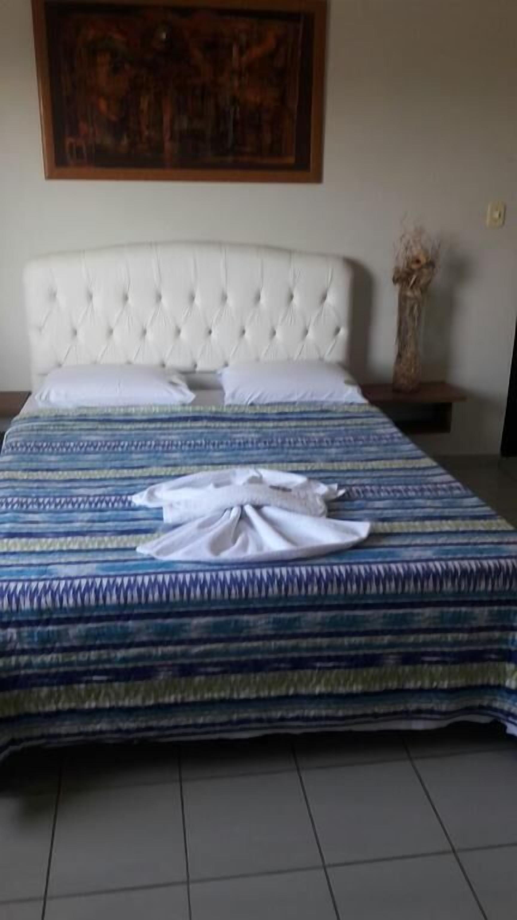 A neatly made bed with a striped bedspread and a folded white towel on top.