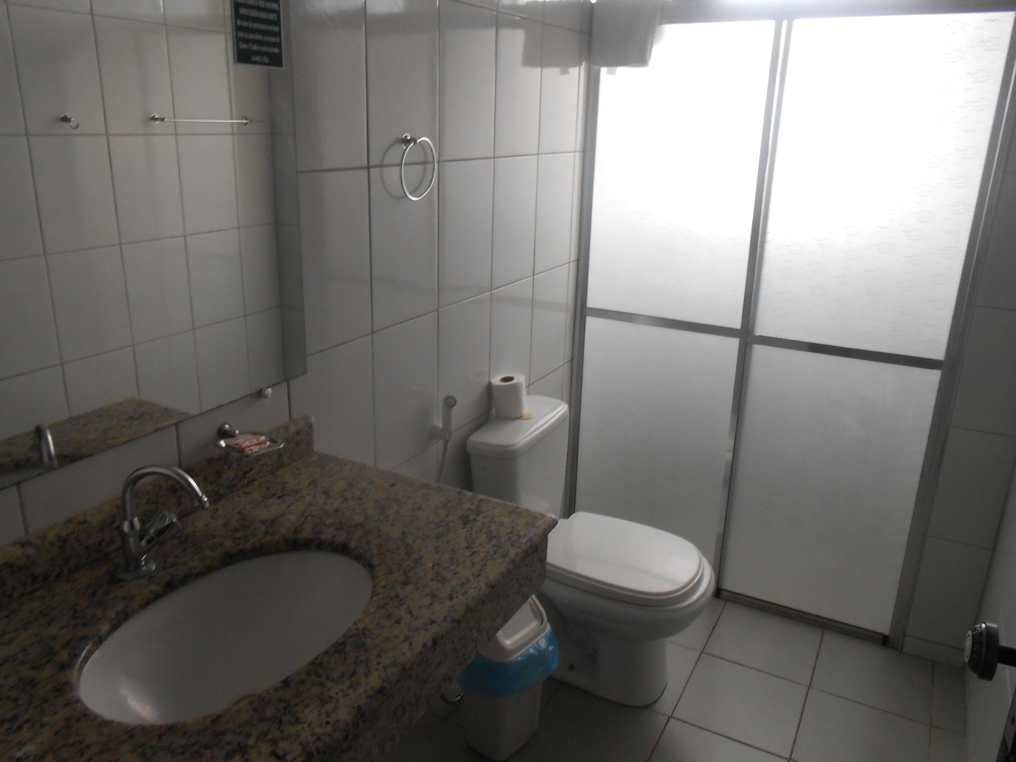 Un baño con lavamanos de granito, inodoro y zona de ducha.
