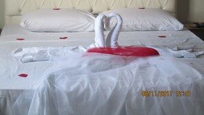 Ein Hotelzimmer mit einem gepolsterten Kopfteil, weißer Bettwäsche und einer auf dem Bett drapierten Handtuchgarnitur.