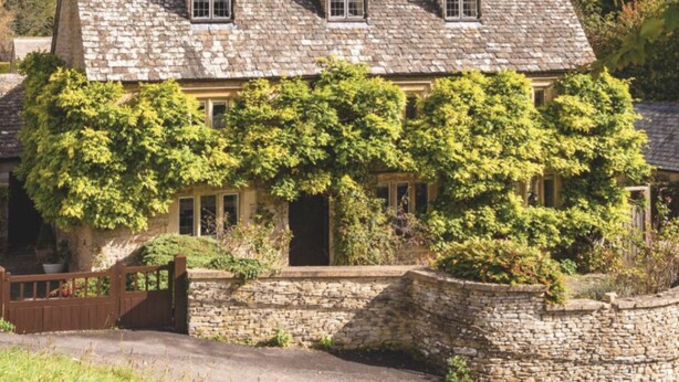 A stone house with a steeply pitched roof, multiple windows, and a wooden gate. - 30% Discount Beautiful converted studio apartment in idyllic Cotswold village! (Cirencester)