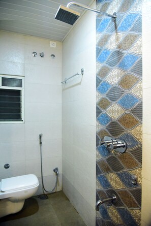 Un baño con inodoro, ducha y pared con diseño.