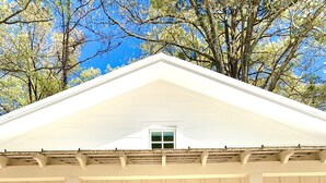 A white building with a gabled roof, two double doors, and a small window above the doors.