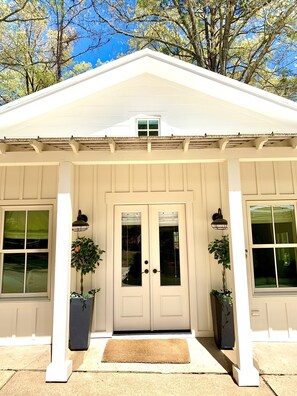 A white building with a gabled roof, two double doors, and a small window above the doors.