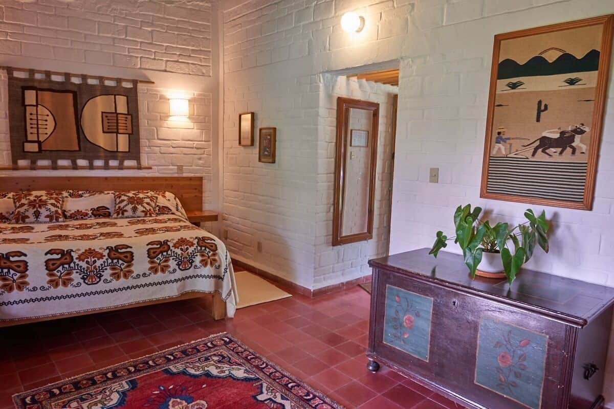 Una habitación con una cama, un armario de madera, una obra de arte en la pared y una puerta.