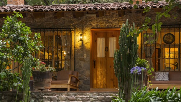 Un bâtiment en pierre avec une porte en bois, des marches menant à un porche et un banc.