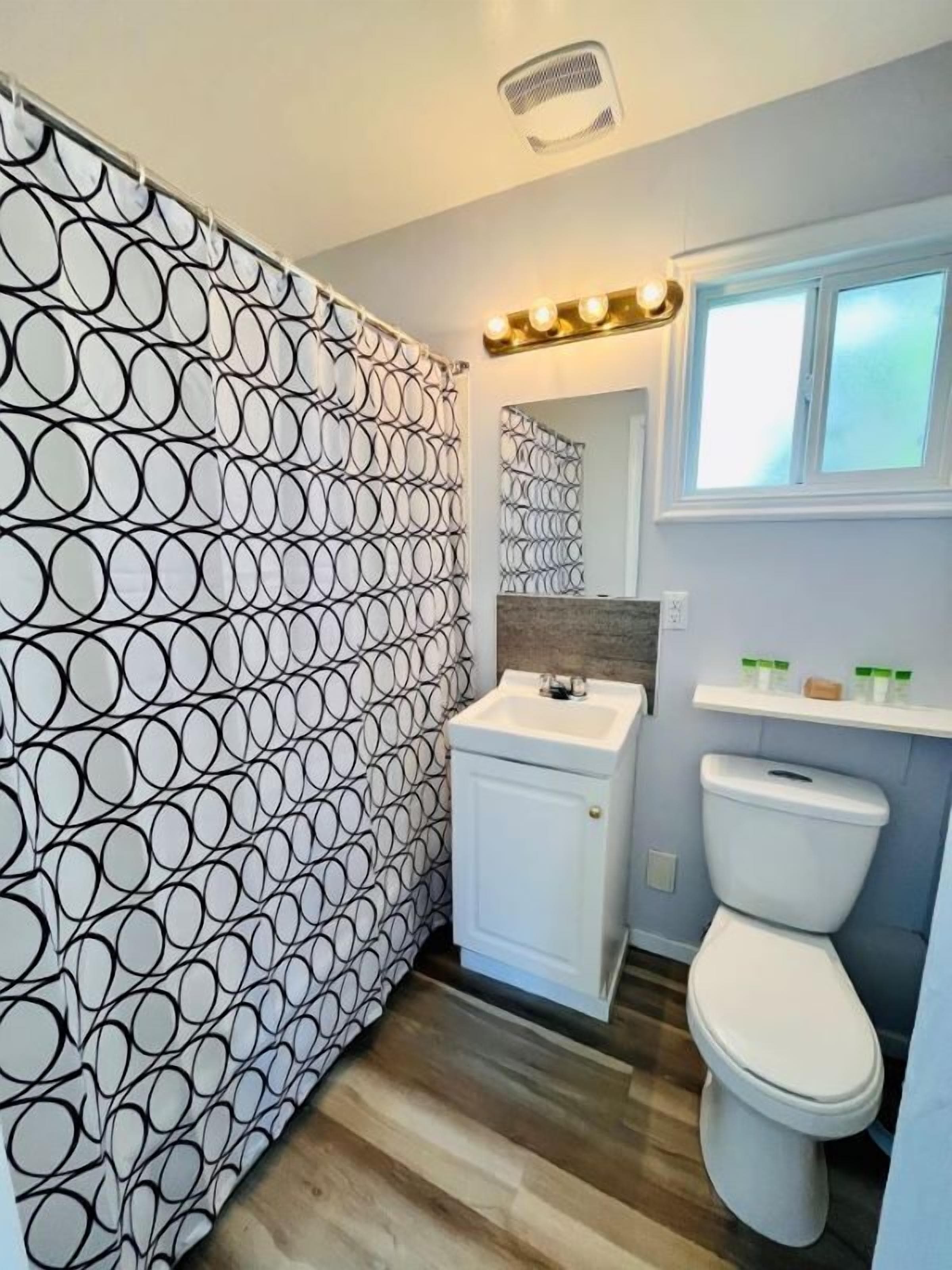 Un baño con pared estampada, un lavabo, un inodoro y una ventana con vistas.