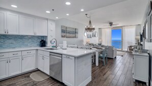 Una cocina moderna con muebles blancos, una isla grande y vista al exterior.