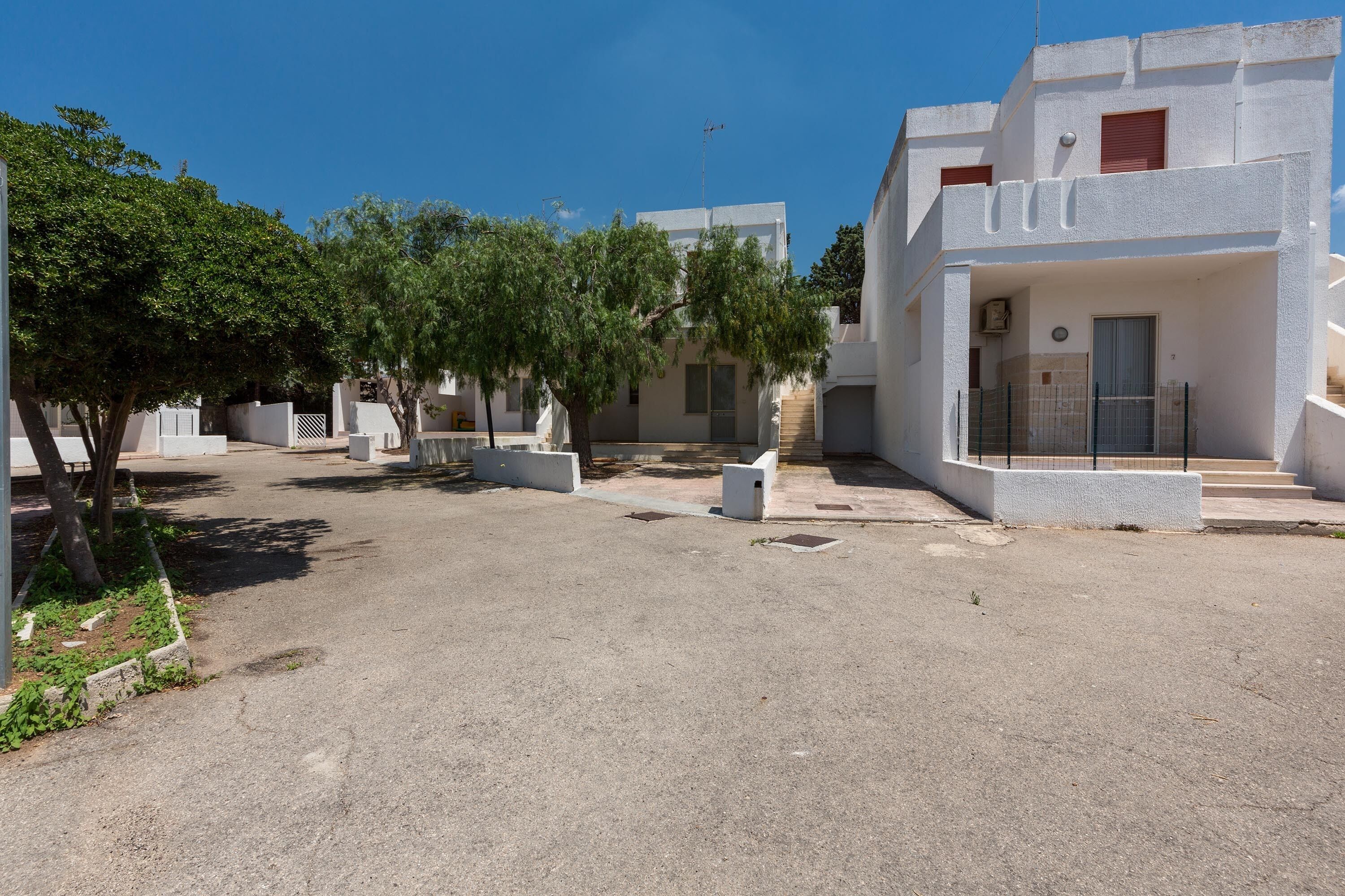 A modern building with a flat roof, white exterior walls, and a small balcony.