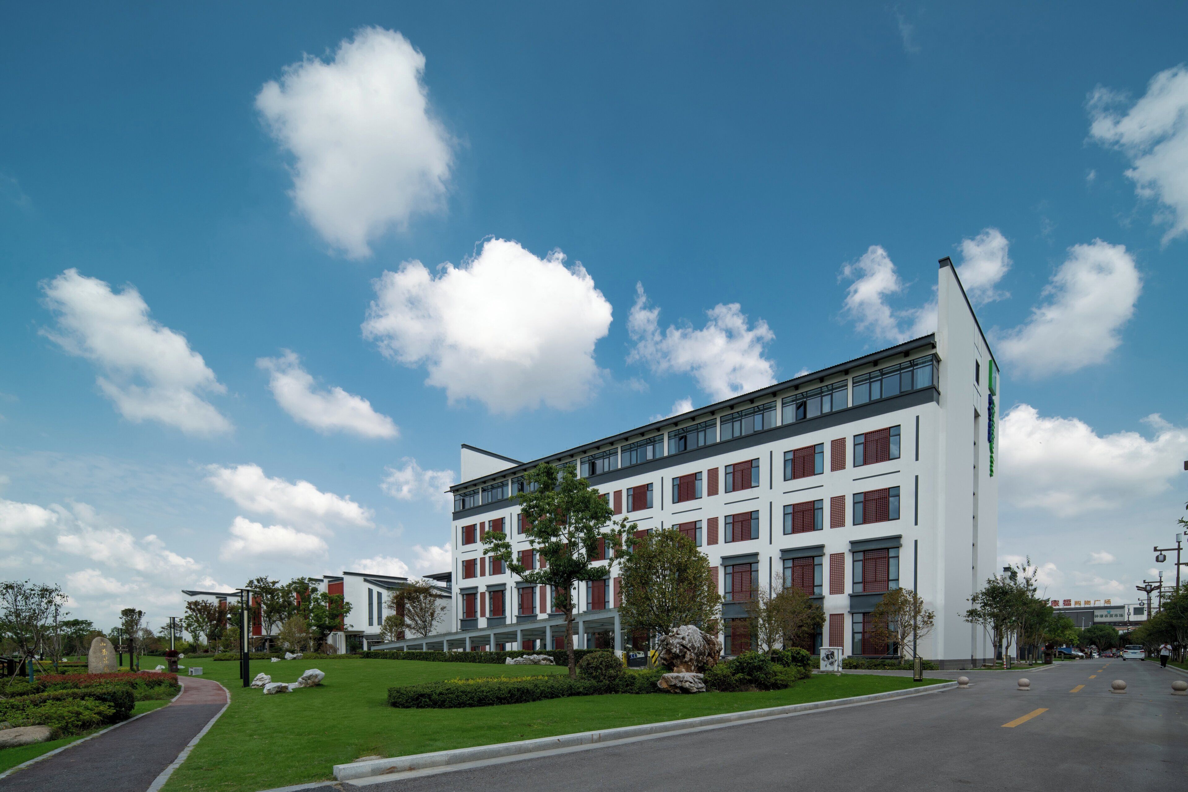A modern building with a flat roof, multiple windows, and a clear sky with clouds.