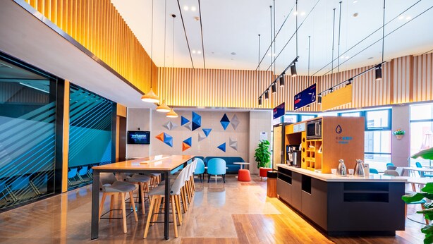A modern interior with a wooden reception desk, seating area, and a staircase. - Holiday Inn Express Pinghu by IHG (Jiaxing)