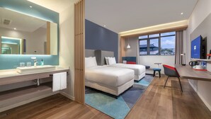 A modern hotel room with a large bed, a desk, a chair, a TV, and a bathroom with a sink and mirror. - Holiday Inn Express Pinghu by IHG (Jiaxing)