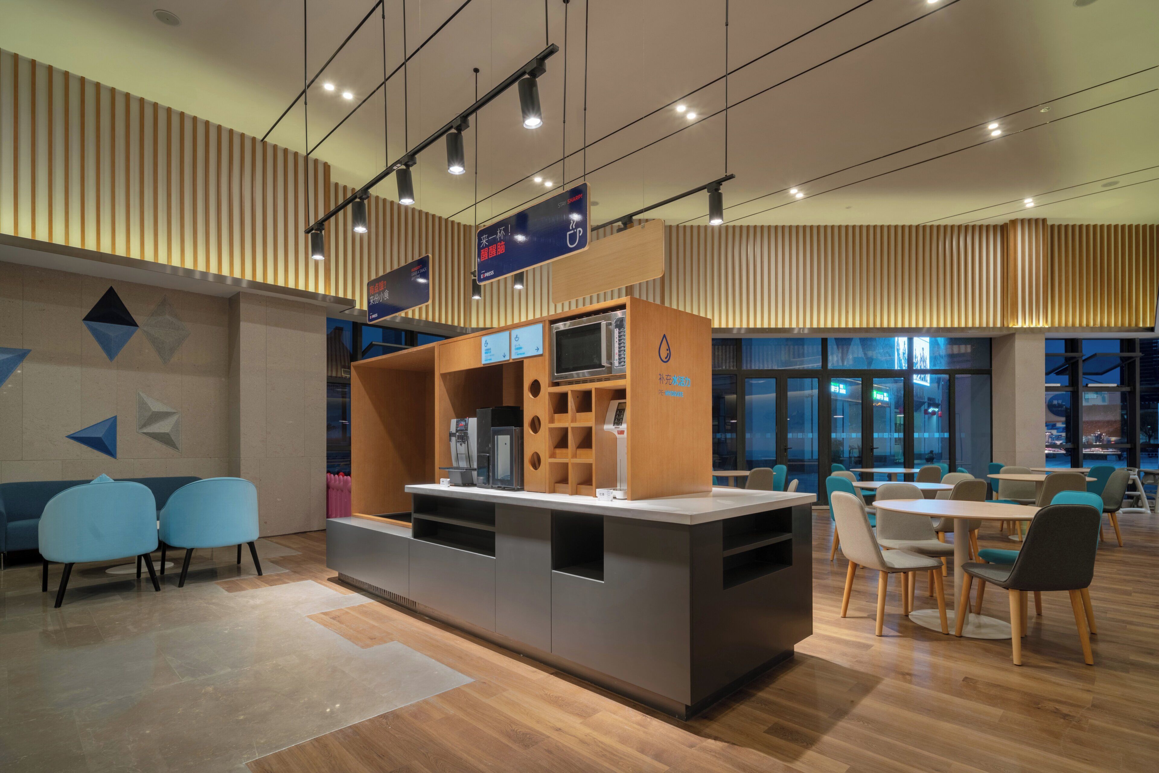 A modern cafe with a coffee machine, seating area, and directional signs.