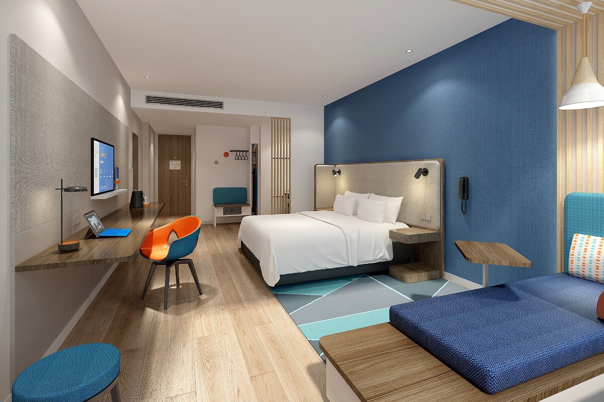 Ein modernes Hotelzimmer mit einem Bett, einem Schreibtisch, einem Stuhl und einer Couch.