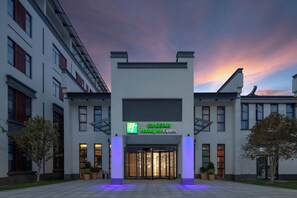 L’entrée d’un hôtel au design moderne, avec une façade en verre et une enseigne « Holiday Inn Express ».