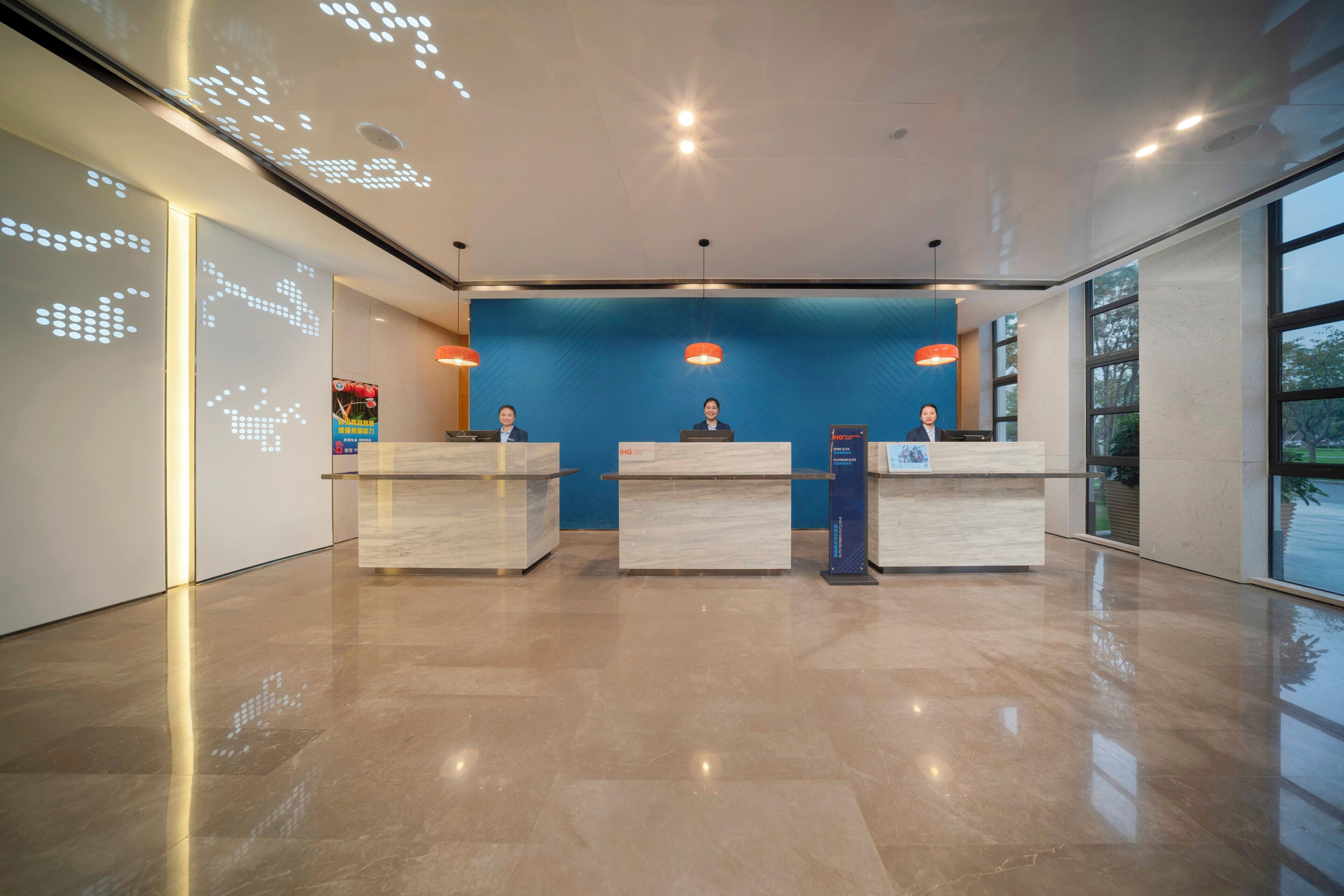 A reception area with three counters, a blue textured wall, and a modern ceiling design.