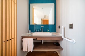 Ein modernes Badezimmer mit einem weißen Waschbecken, einem Spiegel und einer blau gefliesten Wand.